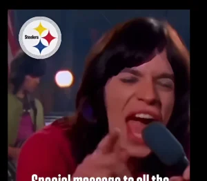 Мэрайя Кэри поет в микрофон, на фоне логотип команды Pittsburgh Steelers.