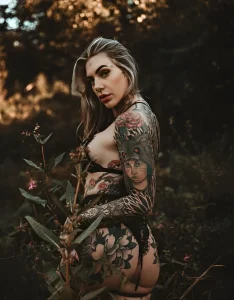Aline mc.lovin.ink, тату-модель, позирует в лесу, демонстрируя свои татуировки.