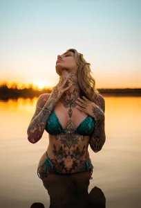 Aline mc.lovin.ink, тату-модель, на фоне заката, демонстрирующая татуировки на теле