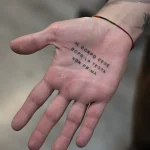 Фото татуировки на ладони: черная надпись 'Il corpo cede dopo la testa, non prima' на открытой руке мужчины.