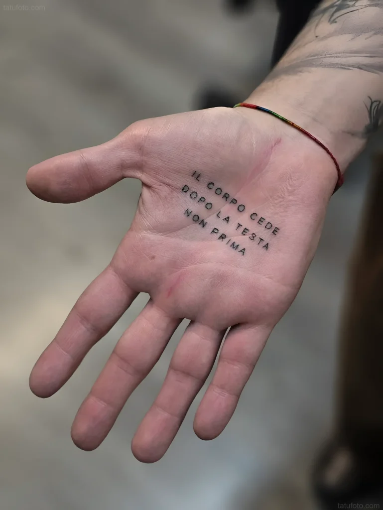 手掌纹身照片:男人张开的手上写着“Il corpo cede dopo la testa, non prima”的黑色文字。