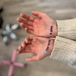 Фото татуировки на ладони: черная надпись 'The world is yours' на обеих руках, минимализм, вдохновляющий дизайн.