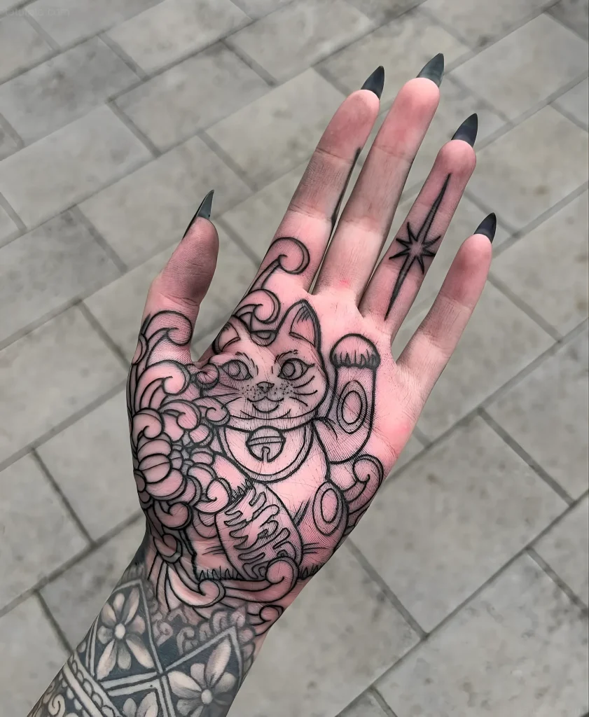 手掌上的黑白纹身,描绘了一只从杯子里探出头的猫,采用老式风格并带有图形元素。
