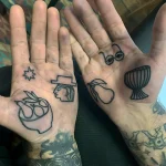 Фото татуировок на обеих ладонях: звезда, голова в шляпе, жест 'Виктория', очки и барабан, выполненные в минималистичном графическом стиле.