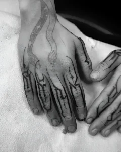 Черно-белая татуировка на пальцах в стиле Blackwork, изображающая стилизованные когти и узор на тыльной стороне ладони.