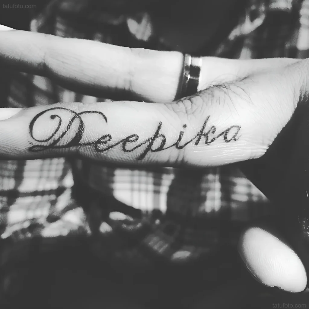 手指上黑白纹身照片:用书法字体纹的'Deepika'名字。