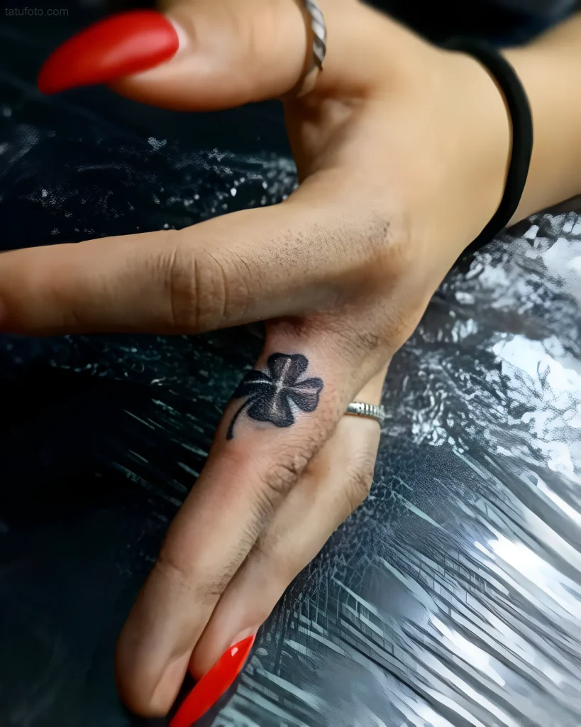 指节上的四叶草黑白纹身照片,极简风格,黑色墨水。