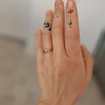 Фотография руки с минималистичными татуировками на пальцах: точки, смайлик, веточка, восклицательный знак.