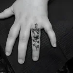Черно-белая татуировка на пальце: роза, пронзенная кинжалом, детальная проработка лепестков и металла