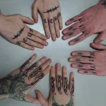 Фотография нескольких рук с минималистичными татуировками на пальцах: колючая проволока, надписи, звезды и капли.