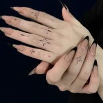 Фото татуировки: минималистичные черные тату в виде звезд и точек на пальцах рук, выполненные тонкой линией.