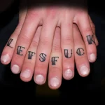 Фото татуировки на пальцах: черная надпись 'LETS FUCK' на фалангах пальцев, вид сверху, темный фон.