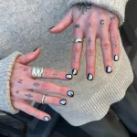 Фото татуировок на пальцах: черные минималистичные символы, луны, крестики, буквы на женской руке.