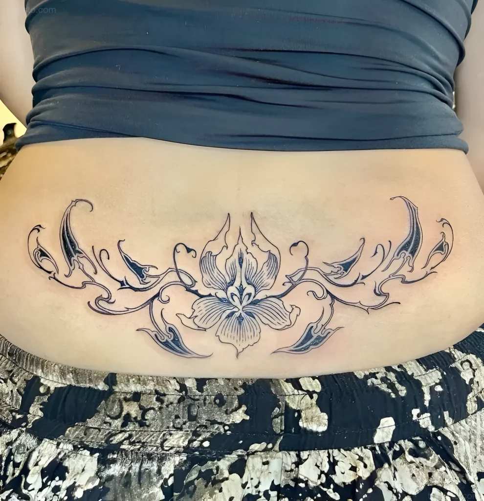 Photo of an orchid tattoo on the lower back, done in a graphic style with an emphasis on smooth lines and petal detail.