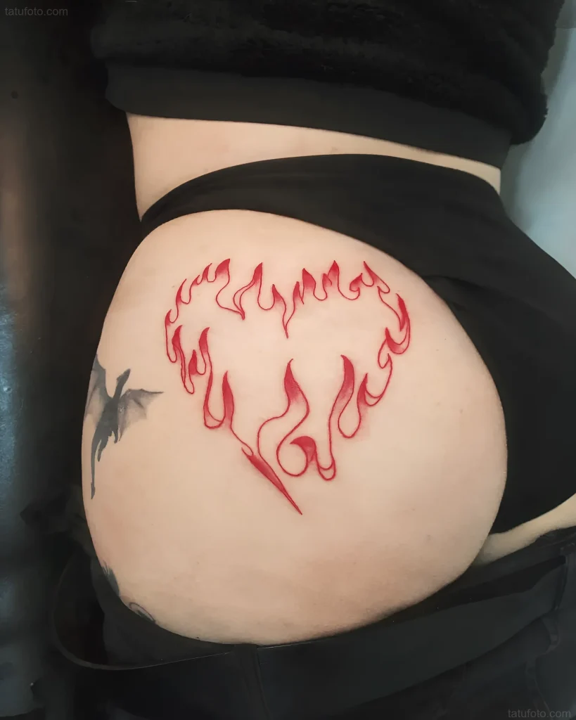 Photo of a buttock tattoo: a red heart stylized as flames, in linework technique.