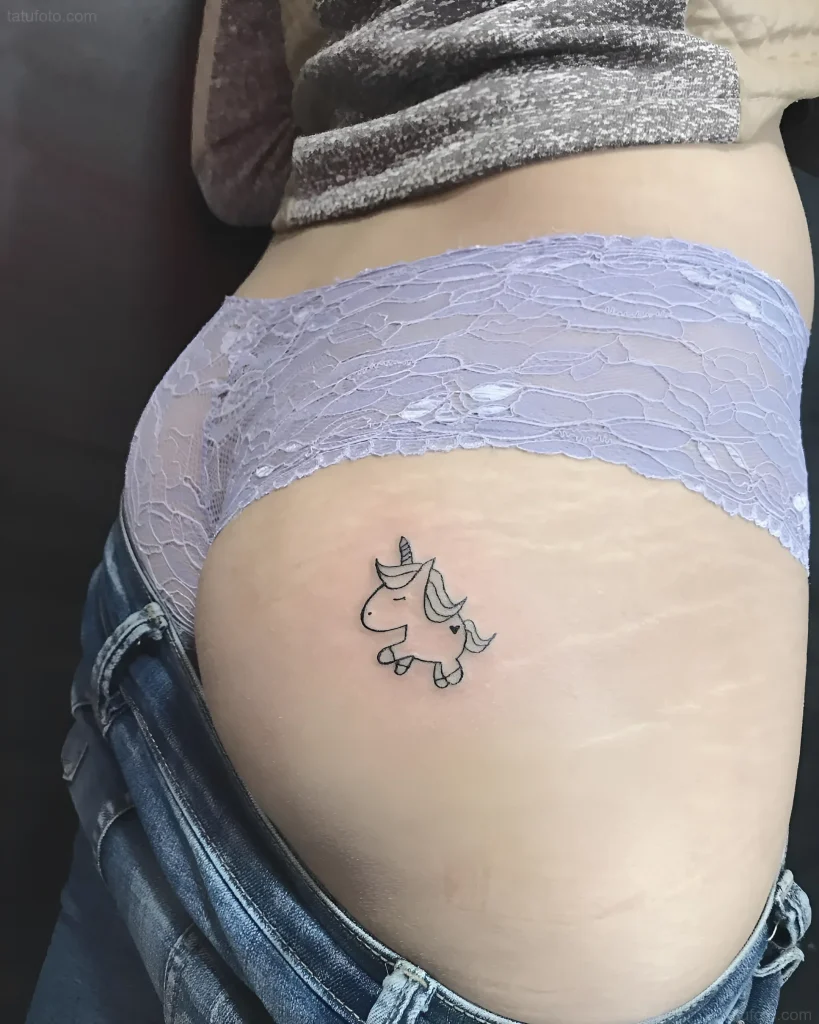 Photograph of a tattoo: a small contour unicorn on a girl's buttock in lace lingerie, side view.