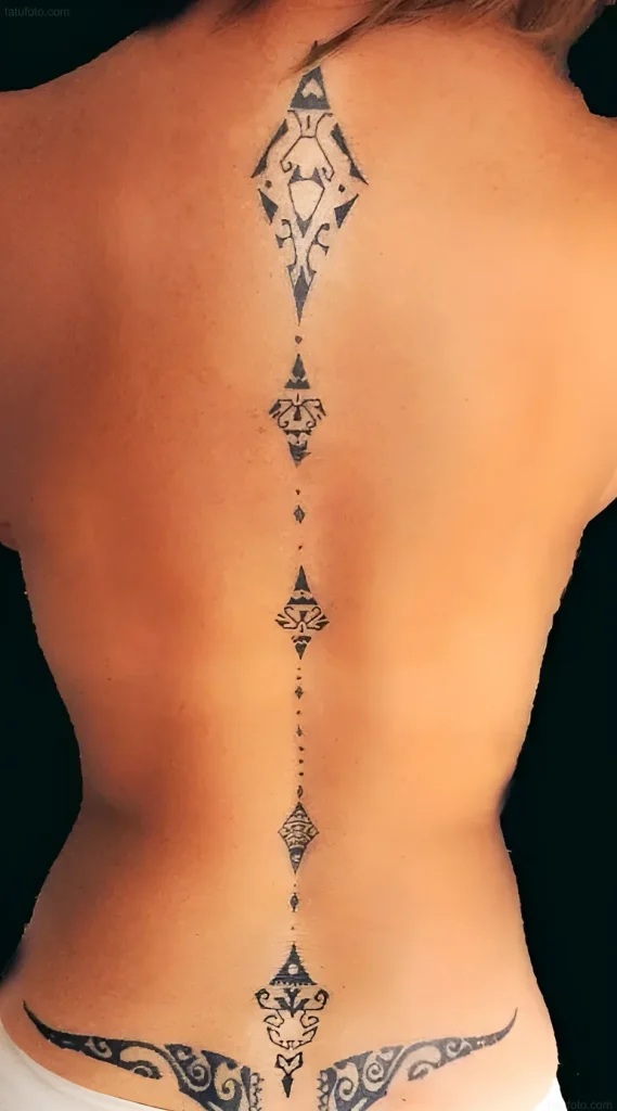 Photo of a tattoo on a woman's back: a long black ornament in Polynesian style, running along the spine from neck to lower back.