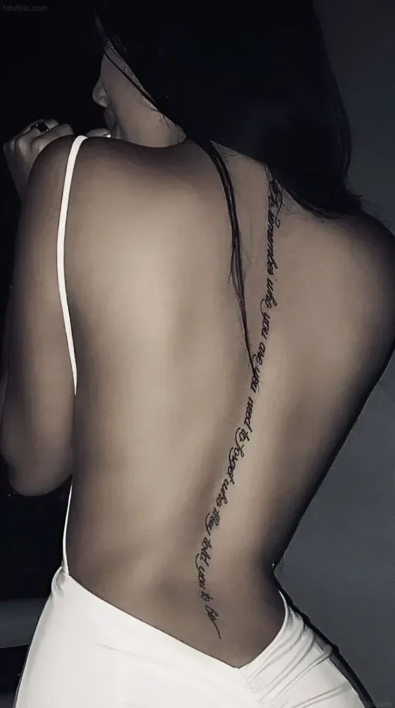 Tattoo photo: an elegant inscription along a girl's spine, done in a fine line, ink, back, minimalism