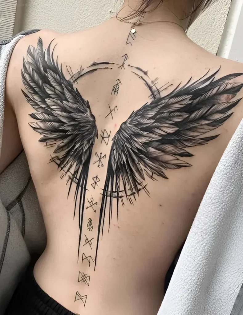 Black and grey tattoo of wings along the spine with runic symbols, done in a realistic style.