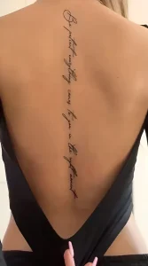 Фото татуировки: Надпись 'Be patient everything comes to you in the right moment' вдоль женского позвоночника, выполненная тонкой линией.