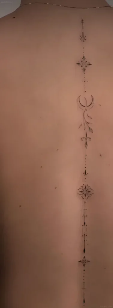 Photograph of a woman's back with a minimalist tattoo along the spine, consisting of a crescent moon, stars, an arrow, and geometric dots.