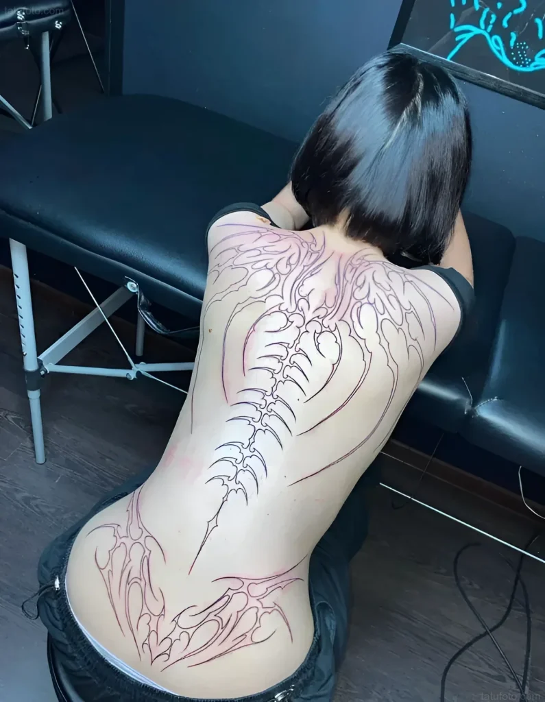 Tattoo sketch of a stylized skeleton running along a girl's spine, done in outline graphic style.