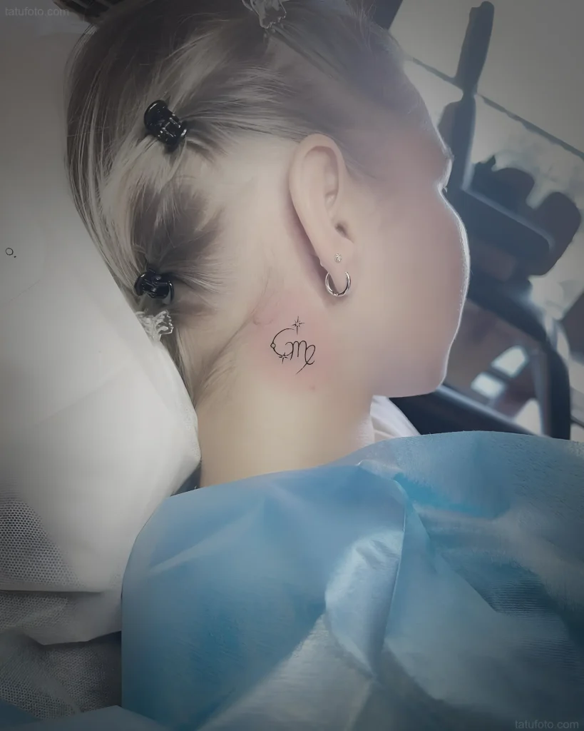 耳后纹身照片:耳后纹有'Om'字样,采用书法风格,并带有一颗小星星,用细线完成.