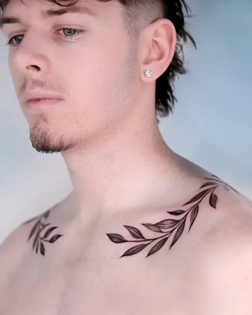 Man with a tattoo of a thin branch elegantly encircling the collarbone, done in a graphic style.