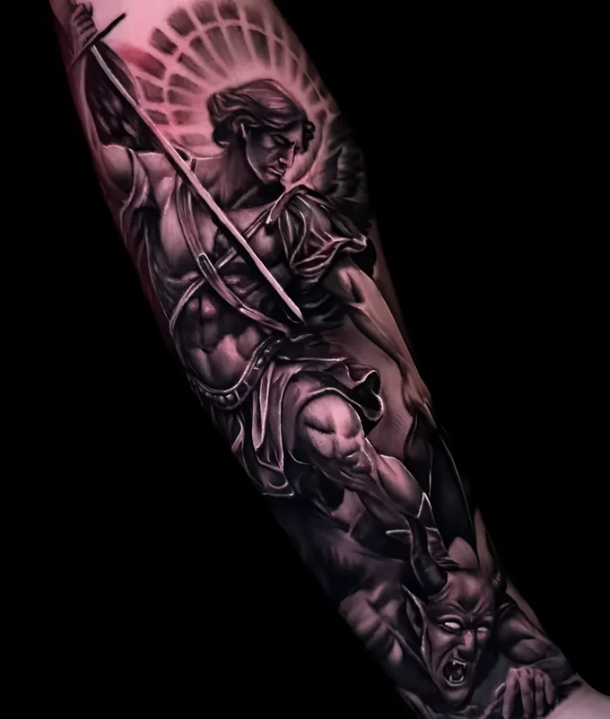 Black and grey realistic tattoo of Archangel Michael fighting a demon on the forearm, with detailed wings and sword.