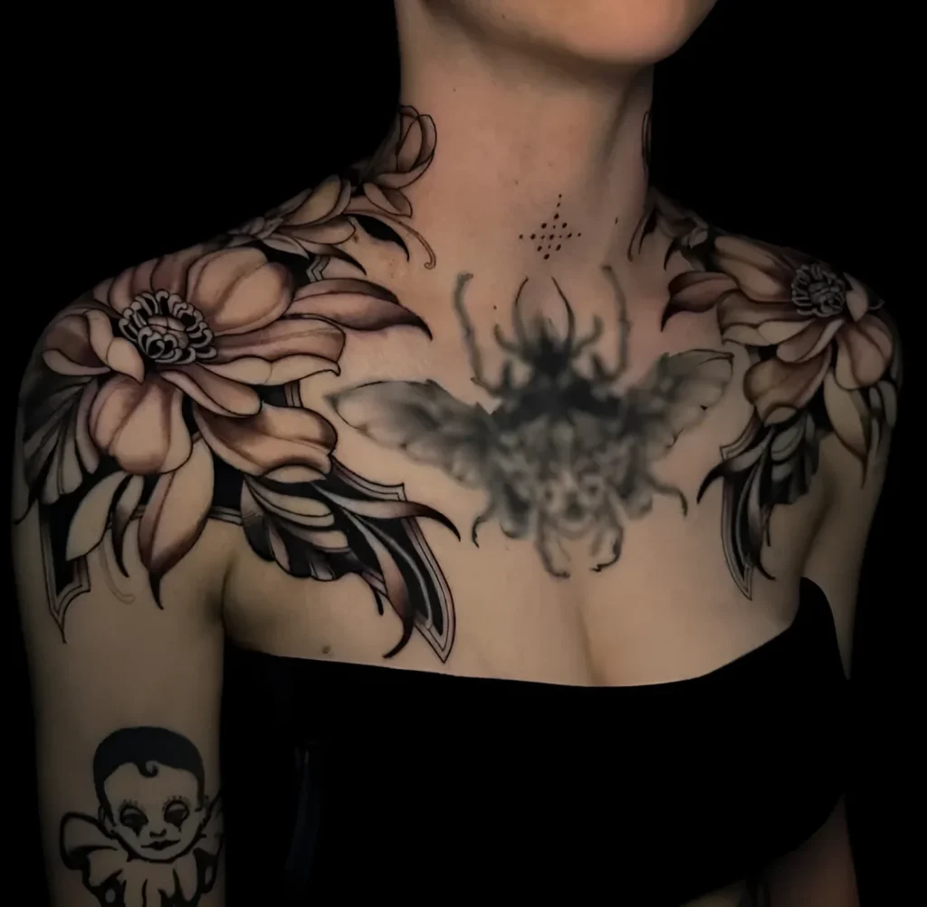 Black and white shoulder tattoo depicting a peony flower and a scarab beetle, done in realistic graphic style.