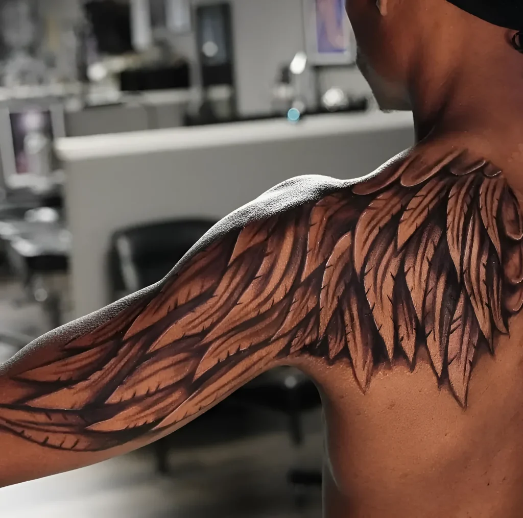Men's tattoo realistic wings on the shoulder blade, done in chiaroscuro technique, rear view.
