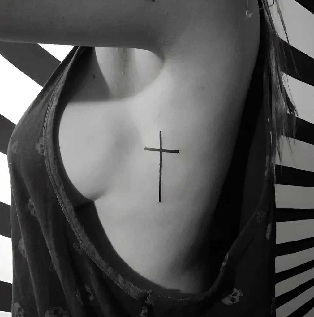 Photographie en noir et blanc d'un tatouage en forme de croix simple, situé sur le flanc d'une femme.