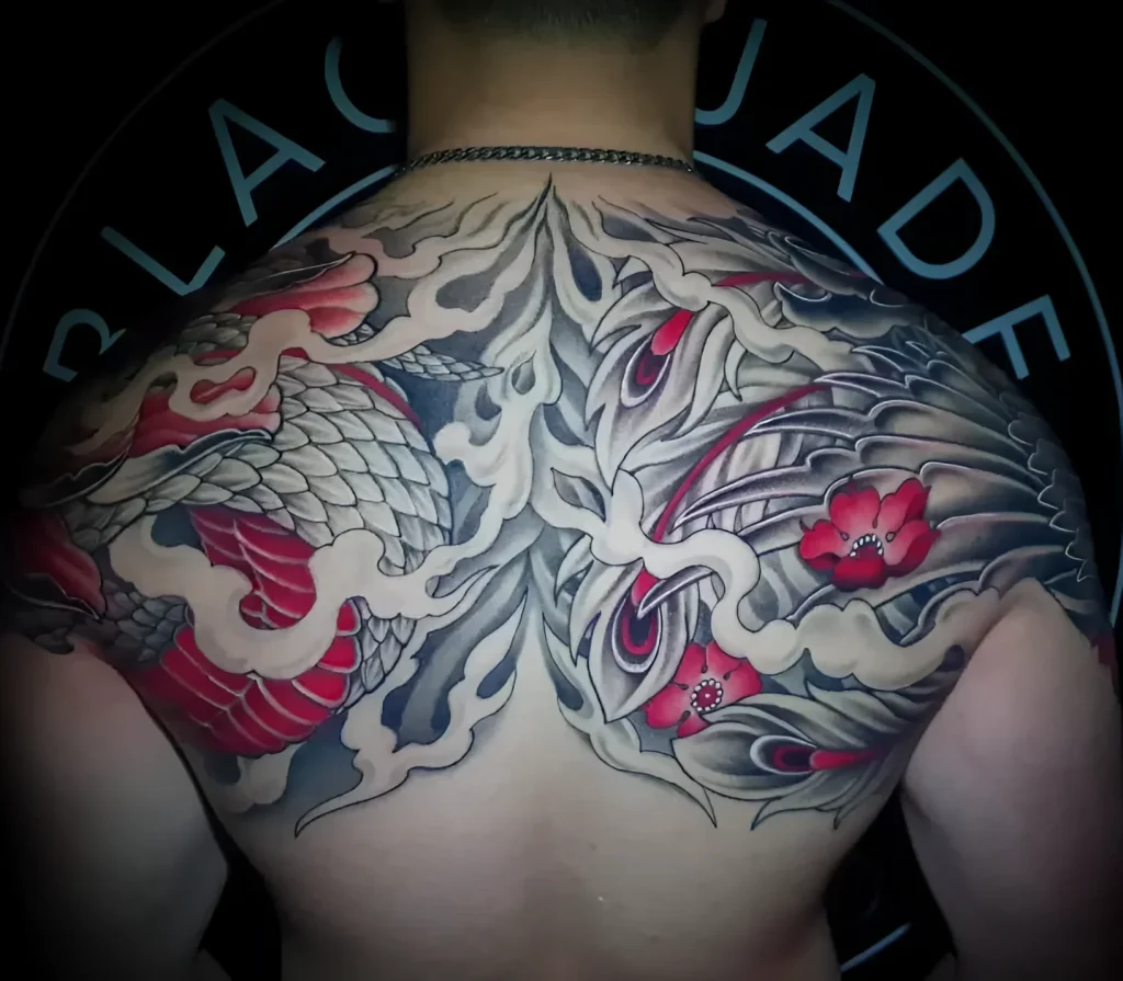 Men's tattoo on the shoulder blade: a realistic dragon in Japanese style, surrounded by waves and sakura flowers.
