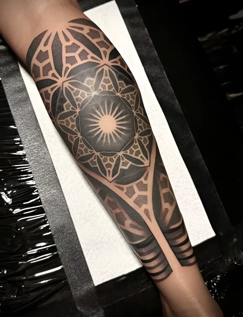 Black and white mandala tattoo in dotwork style, done on the calf, with an emphasis on symmetry and detail.