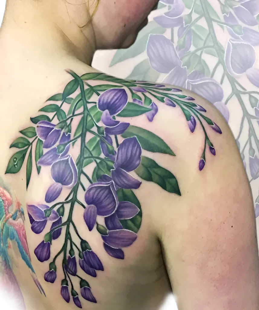 Photo of a wisteria tattoo on the shoulder blade, done in watercolor technique using purple and green shades.