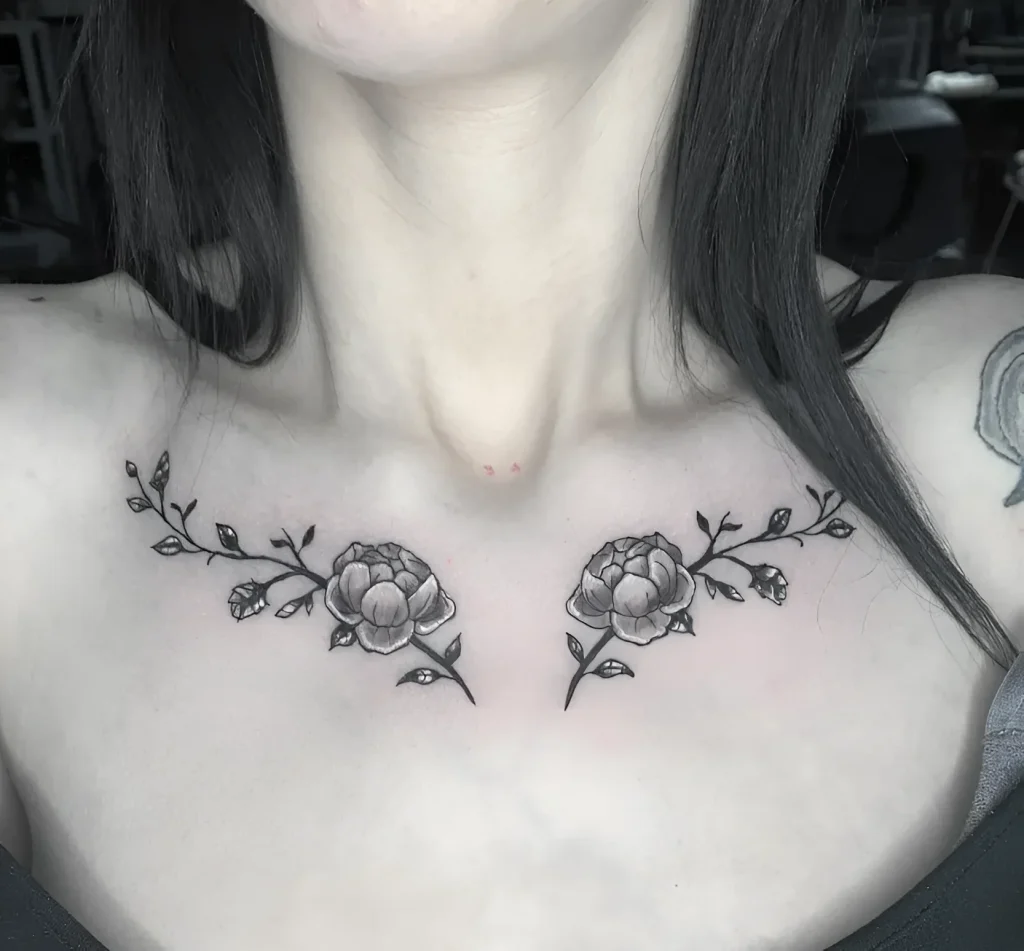 Black and white tattoo with peonies, placed on the girl's collarbone, with detailed rendering of petals and leaves.