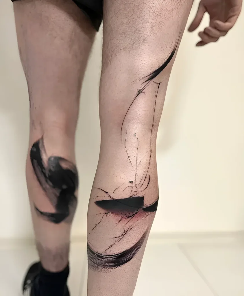 Black and grey abstract tattoo on the calf, mimicking brush strokes, with an emphasis on dynamics and the shape of the knee.