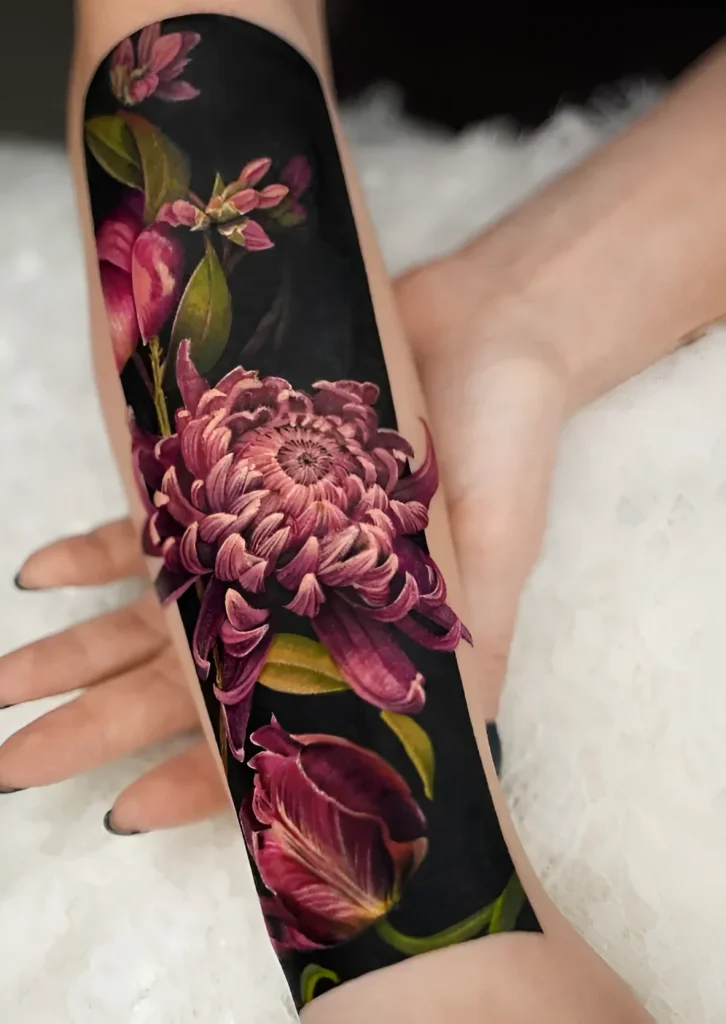 Tattoo photo: realistic crimson chrysanthemum wrapping around the forearm, with detailed rendering of petals and buds.