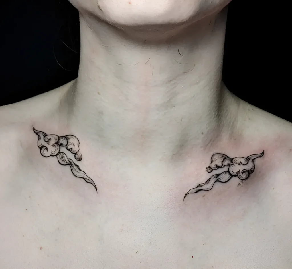 Black and white tattoo in the style of traditional Japanese painting – two clouds, placed symmetrically under the girl's collarbones.