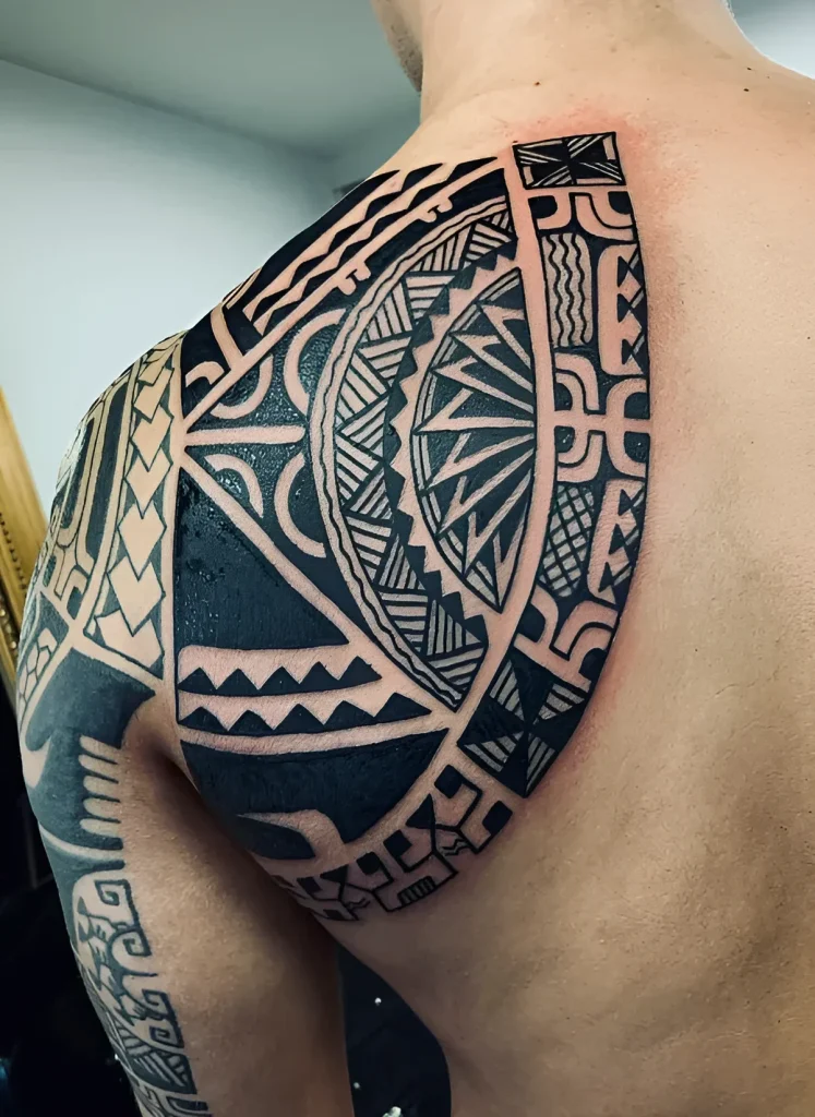 Photo of a Polynesian ornament style tattoo on a man's shoulder blade, with emphasis on the shoulder and upper back.