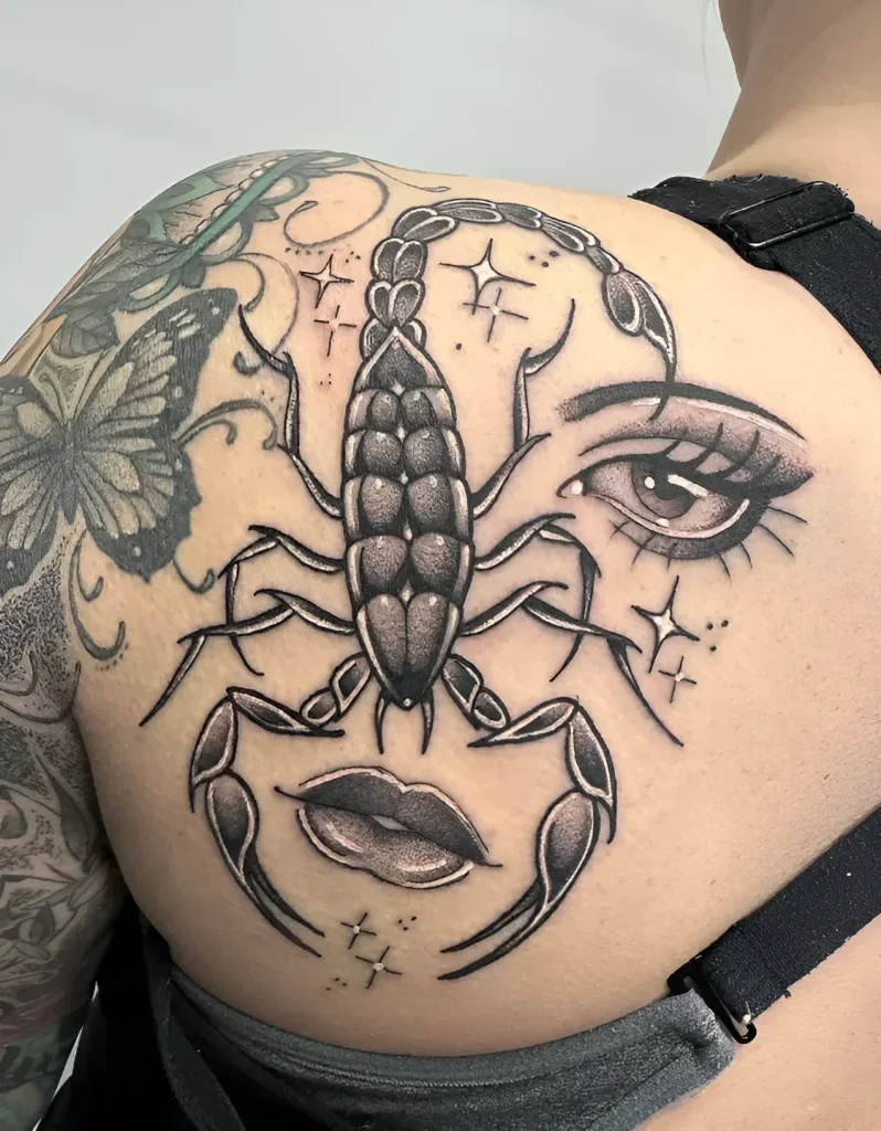 Black and white tattoo on the shoulder blade: a female face integrated into a scorpion silhouette, with added star accents.