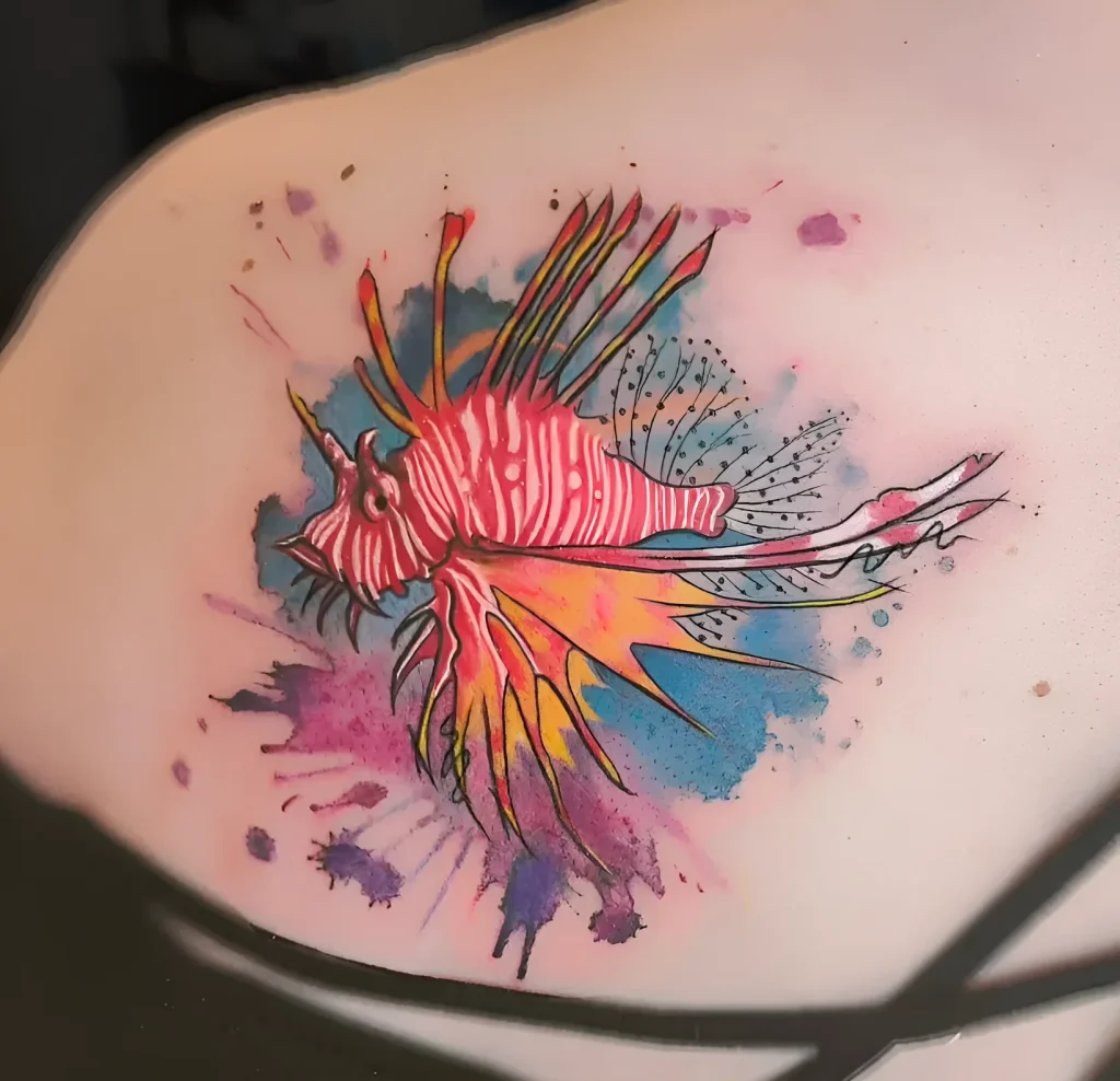 Photo of a watercolor stingray tattoo on a woman's shoulder blade, using bright pink, yellow, blue, and purple shades.