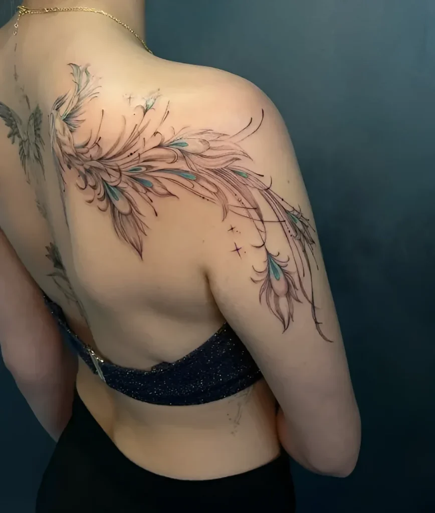 Photo of a tattoo: an elegant wing done in watercolor and graphic technique on a woman's shoulder blade, with added small stars.