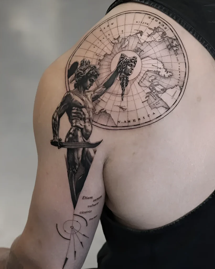 Black and grey realistic tattoo on the shoulder blade: an angel holding a sword against the backdrop of an antique globe with a world map.