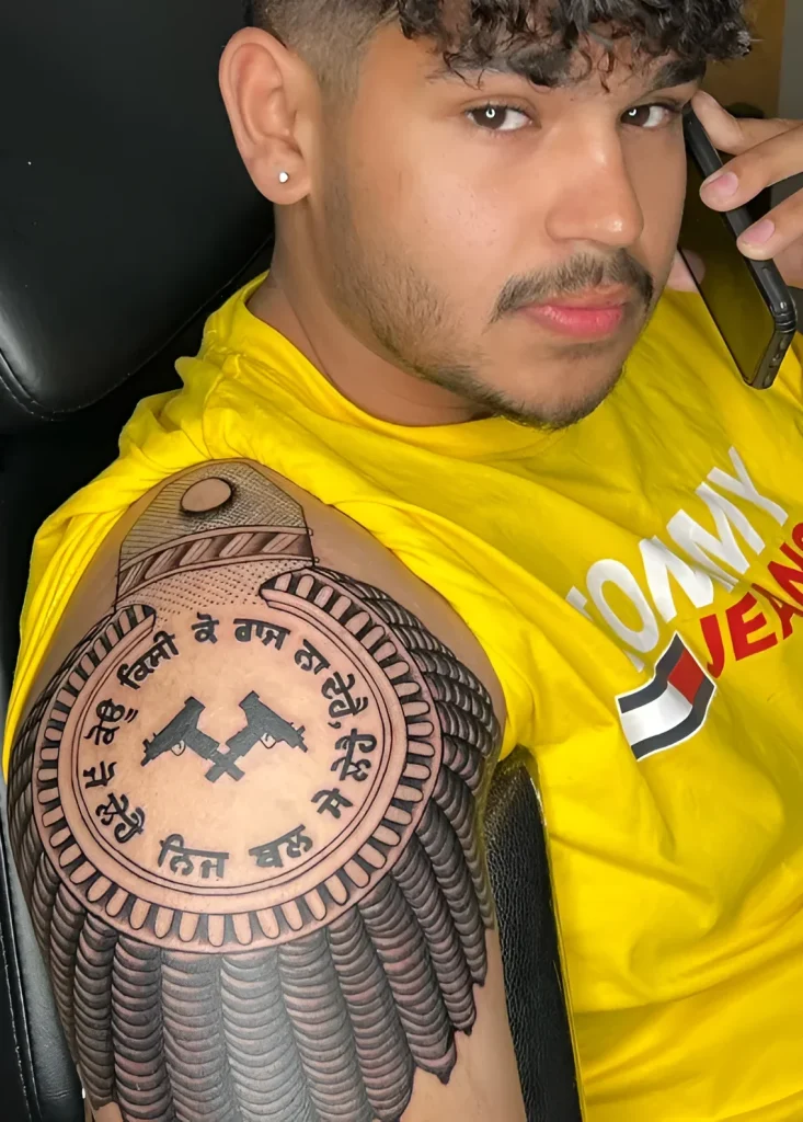 Man's shoulder tattoo in graphic style: two pistols in a circle with Gujarati text.