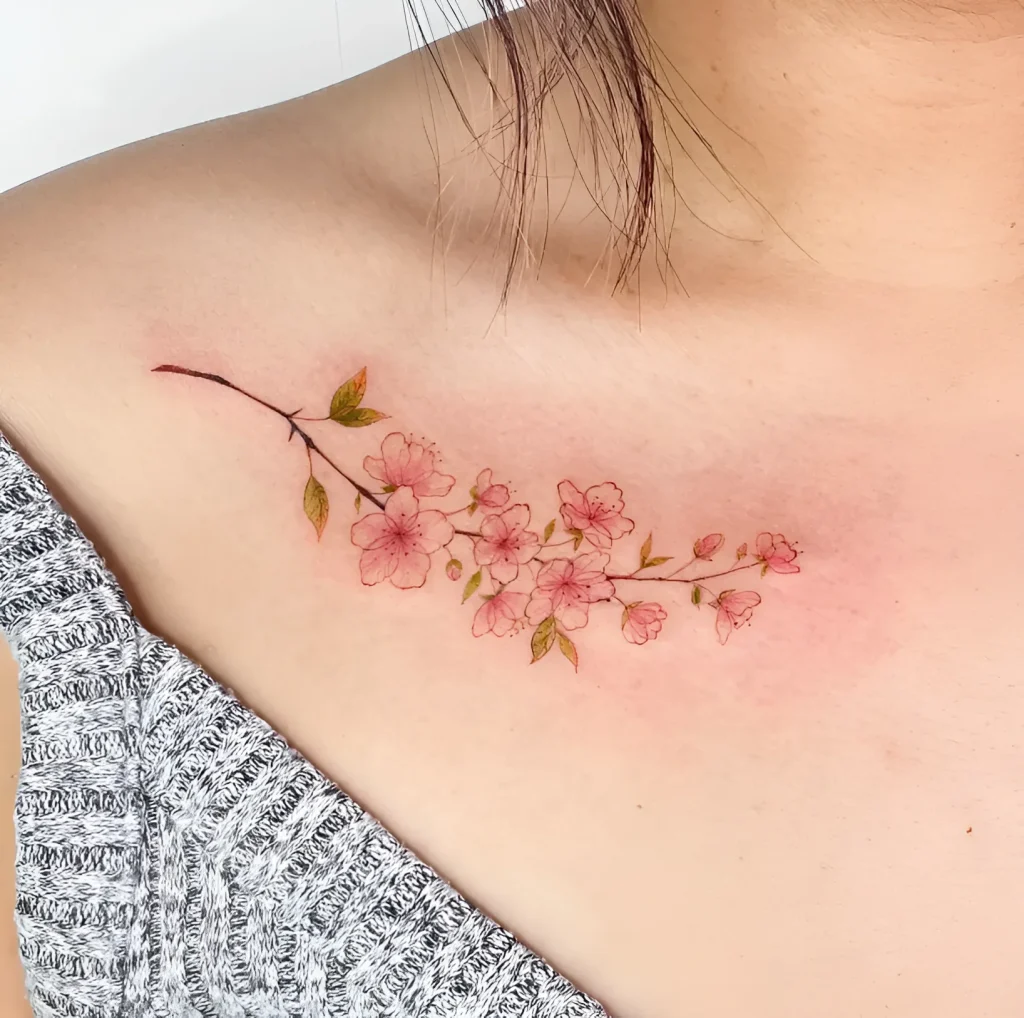 Women's watercolor tattoo of a blooming sakura branch on the collarbone, delicate pink and green tones