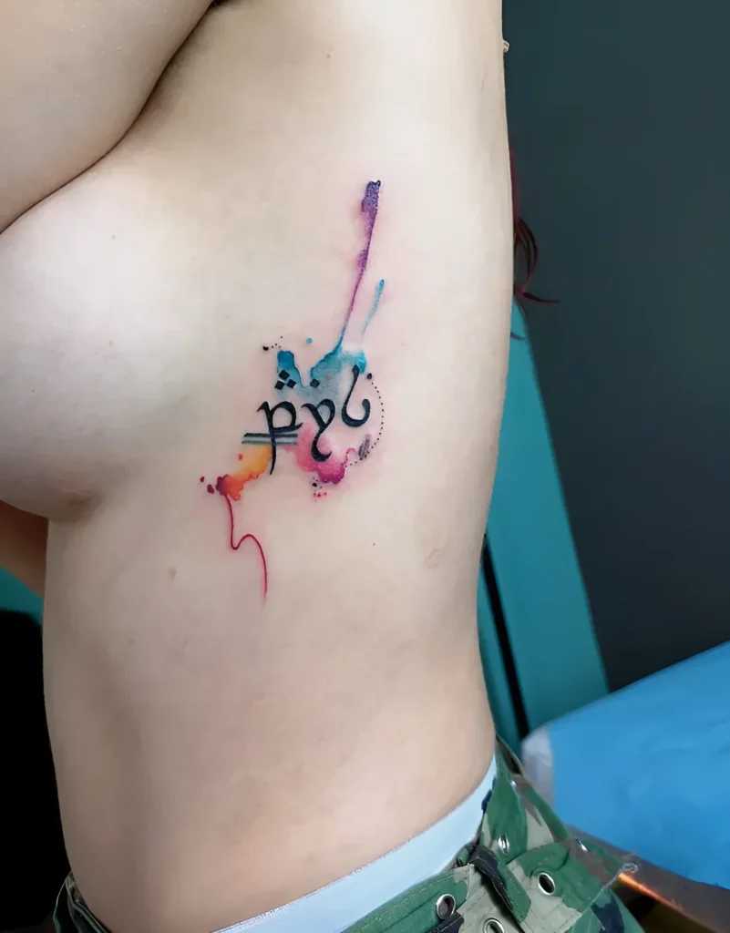 Photo d'un tatouage sur le flanc : inscription en langue elfique en aquarelle, réalisée sur un corps féminin.