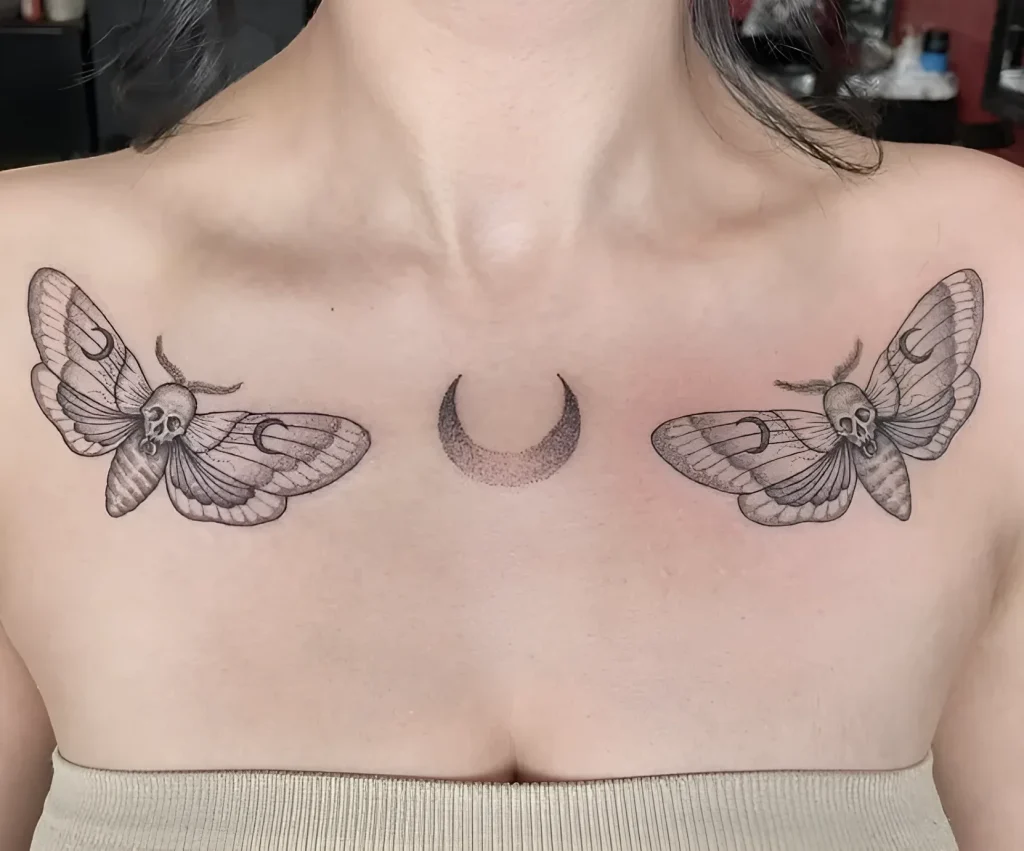 Black and white collarbone tattoo: two moths with skulls on their wings and a crescent moon, done in dotwork technique.