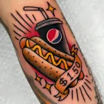 Яркая татуировка хот-дога в стиле олд скул с напитком Pepsi и ценником $1.50 на руке