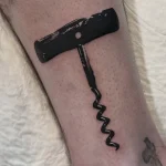 Черно-белая татуировка штопора на икре, выполненная в реалистичном стиле с акцентом на текстуру металла и дерева.